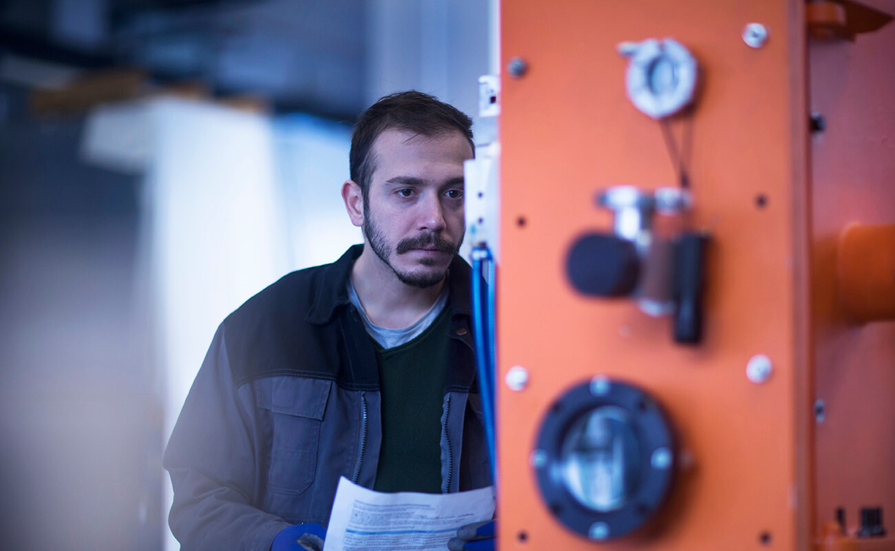 Engineer Holding Paperwork Operating Control Panel